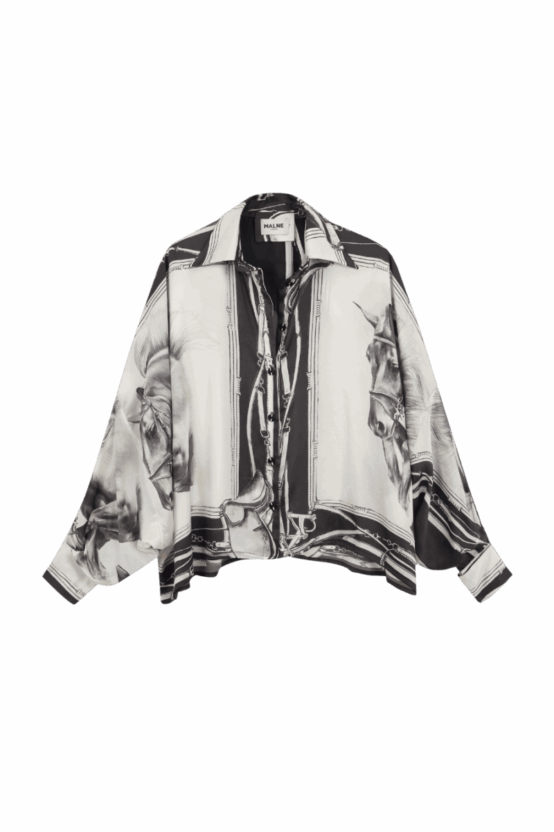Blusa fluida en seda estampada con ilustraciones ecuestres en blanco y negro, corte amplio y cuello clásico. Una prenda sofisticada de aire artístico y esencia atemporal