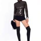 El top de lentejuelas negras, de cuello alto y silueta ajustada, destila sofisticación y brillo con un aire futurista
