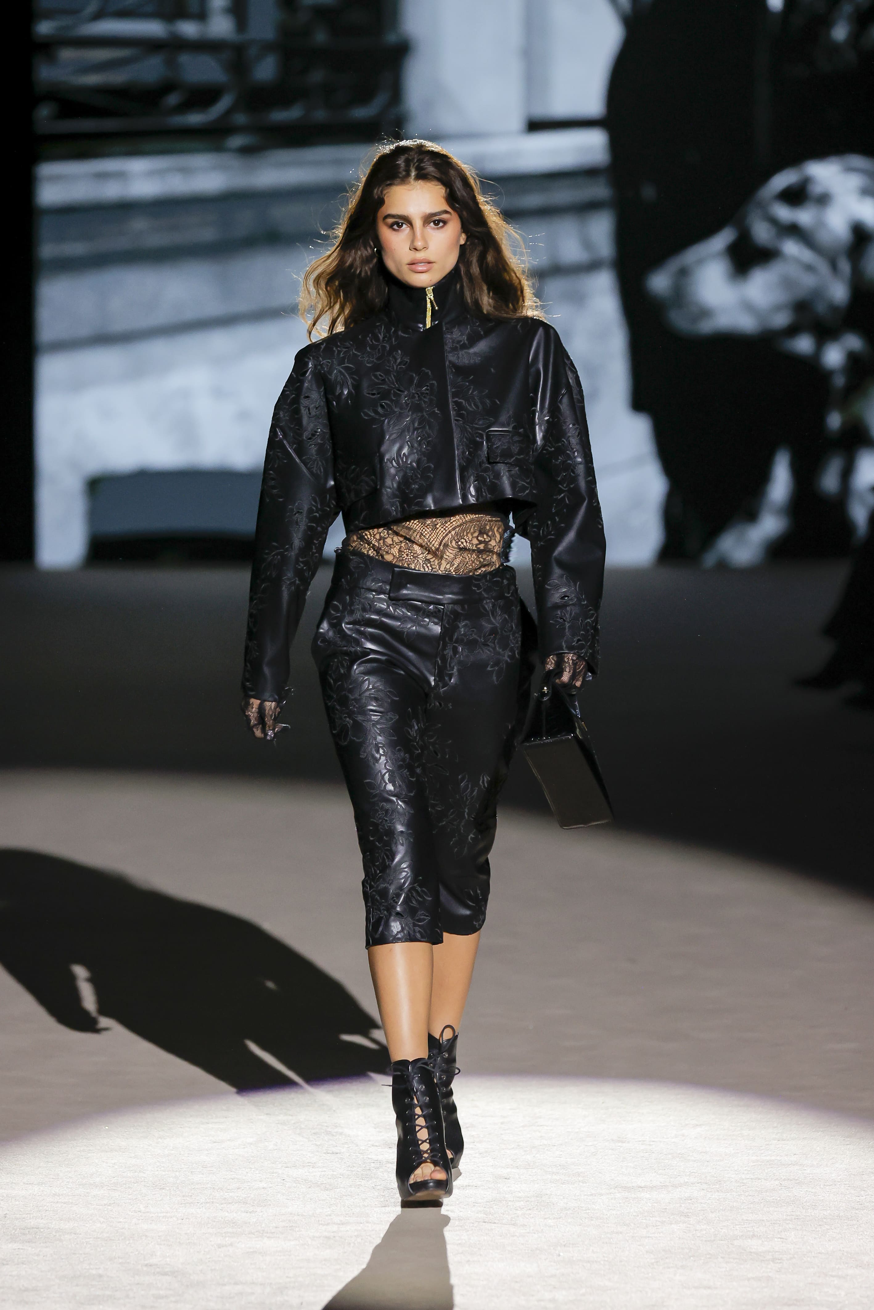 Modelo desfilando con un diseño de Malne en la Mercedes-Benz Fashion Week Madrid en marzo de 2026 con conjunto negro estructurado y botines de cordones.
