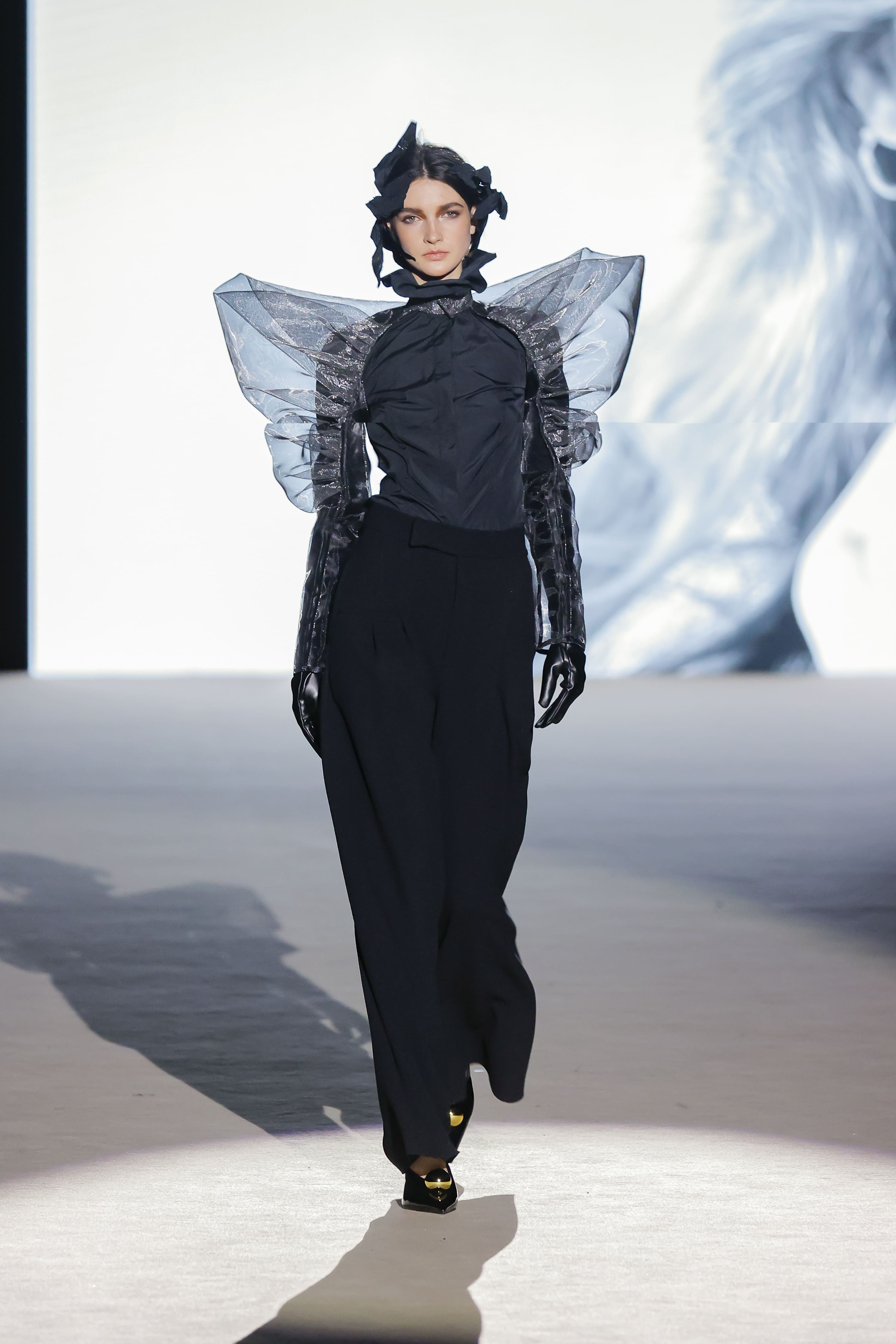 Modelo con blusa negra con mangas estructuradas y pantalón de Malne en la Mercedes-Benz Fashion Week Madrid marzo de 2026 con detalles translúcidos.