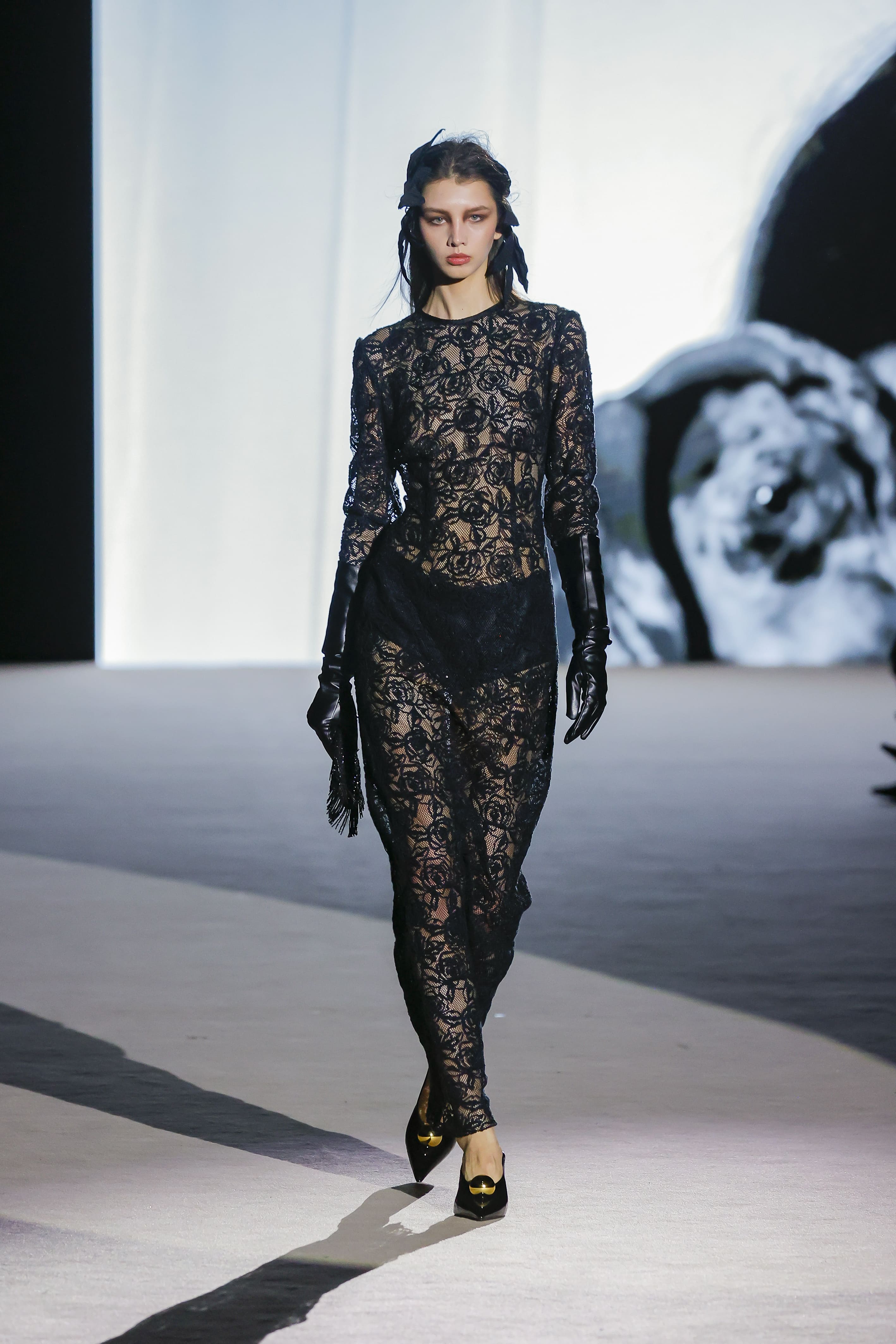 Modelo con vestido negro de encaje transparente y guantes largos de Malne en la Mercedes-Benz Fashion Week Madrid marzo de 2026.
