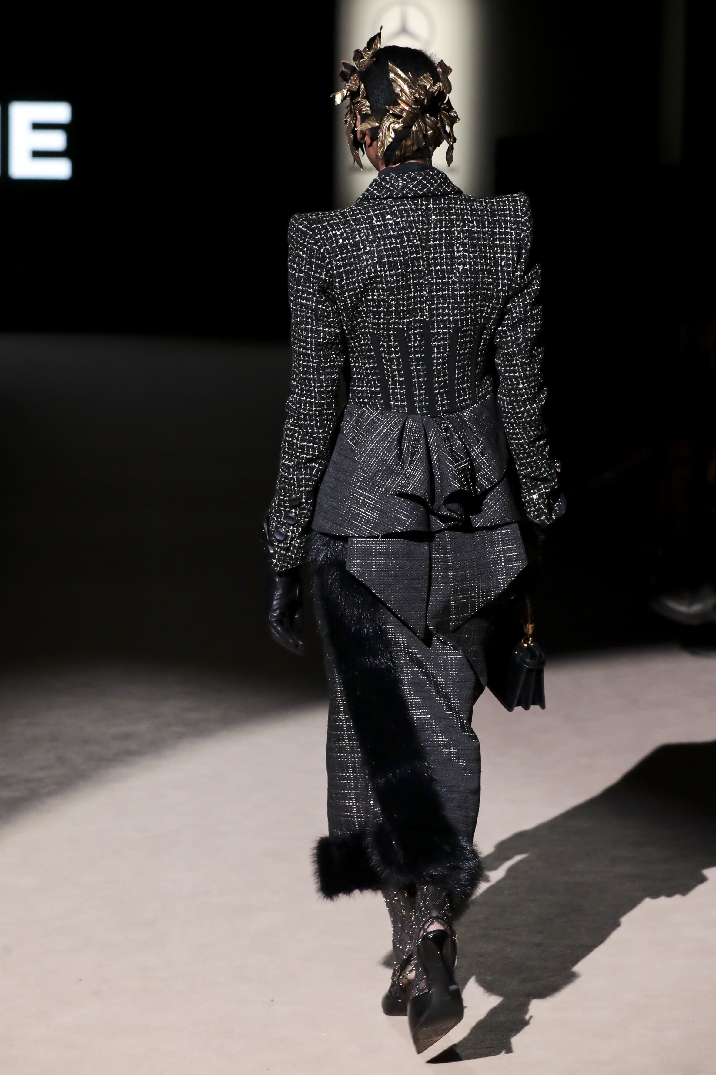 Modelo desfilando de espaldas con conjunto negro texturizado de Malne en la Mercedes-Benz Fashion Week Madrid marzo de 2026 con silueta estructurada.