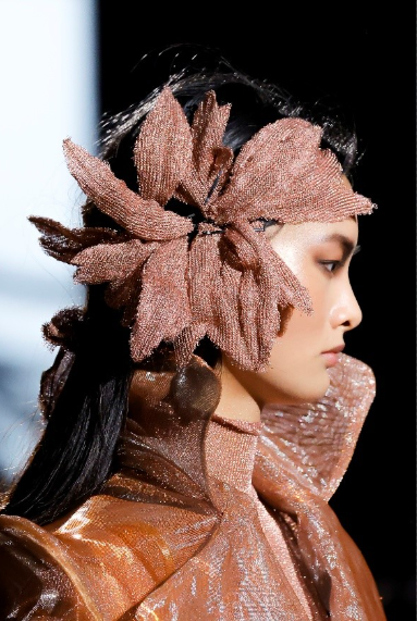 Modelo de Malne con un tocado de gran tamaño en forma de flor durante un desfile de moda