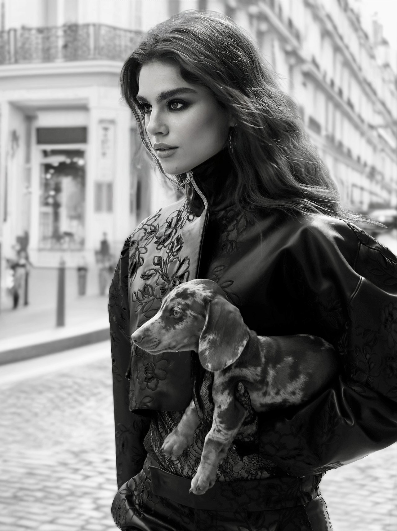 Model wearing an embroidered Malne jacket and holding a puppy, in black and white