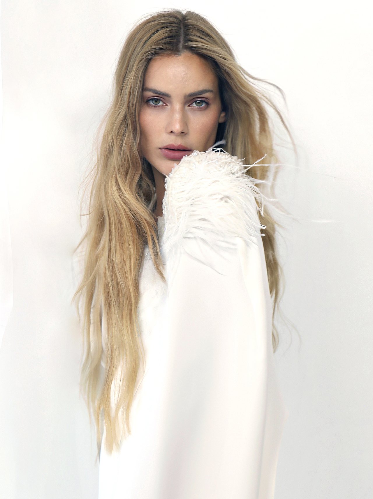 Model wearing a white Malne dress with feather sleeves