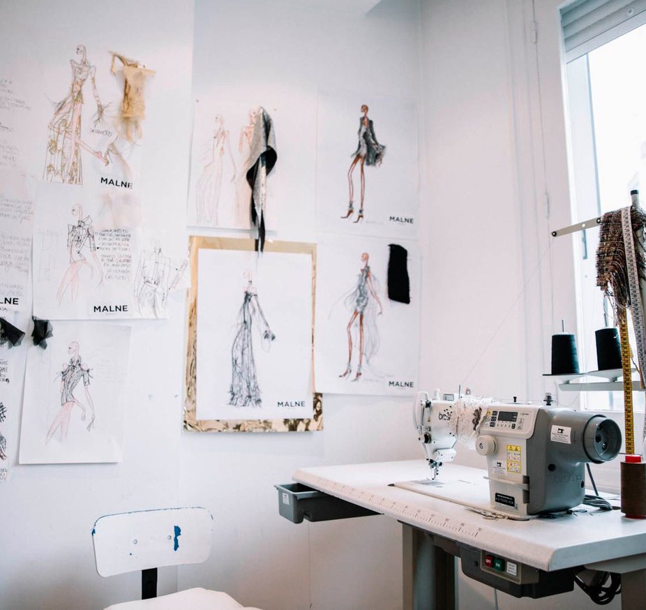 Pattern-making workshop at the Malne atelier, with a sewing machine and sketches on the wall
